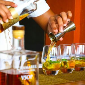 A bartender expertly pours cocktails in glasses on a bar counter.